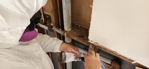 man fixing a wall with asbestos